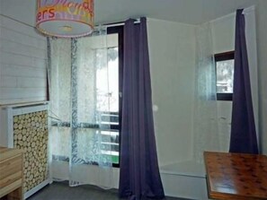 A corner room with a wooden cabinet, a window with curtains, and a door.
