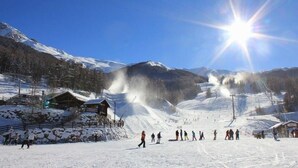 Une piste de ski enneigée, sous un ciel dégagé et un soleil éclatant.
