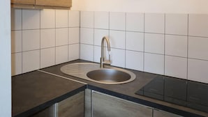 A kitchen with a double sink, wooden cabinets, and white tiled backsplash.