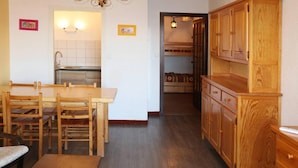 A kitchen with wooden cabinets, a dining table with chairs, and a bench.