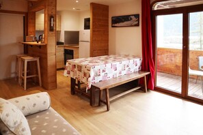 Una habitación acogedora con una mesa de madera, un sofá y una zona de cocina.