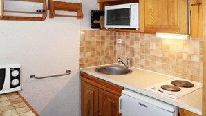 A compact kitchen with a sink, stove, and microwave.
