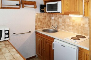 A compact kitchen with a sink, stove, and microwave.