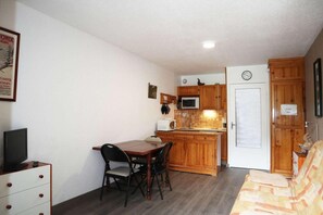 A compact kitchen with wooden cabinets, a dining table, and chairs. - 15m from ski slopes, 8th floor, view ski slopes, balcony, tv, ski locker, 28m², Les Orres (Les Orres)