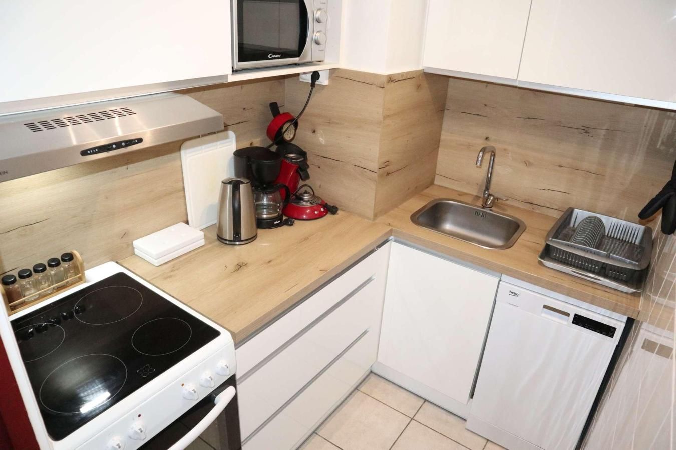 A compact kitchen with a stove, microwave, sink, and a dishwasher.
