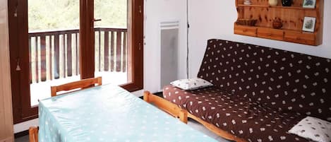 A room with a bed, a table, and a wooden shelf with decorative items.