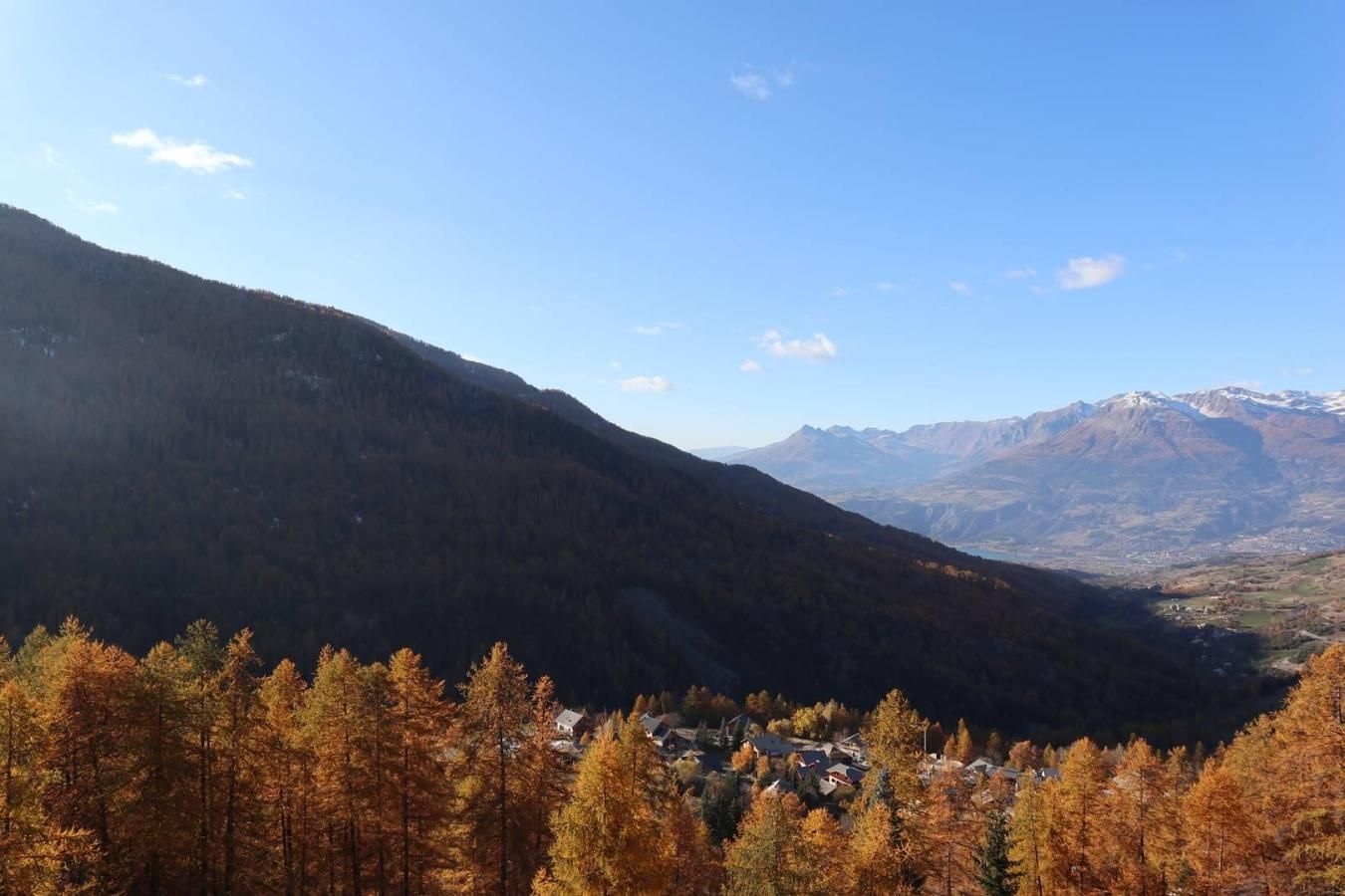 A mountainous landscape with a valley and a small settlement.