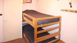 Uma beliche com estrutura de madeira e roupa de cama escura.