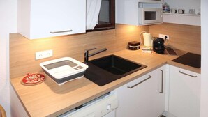 Uma cozinha compacta com pia, micro-ondas e lava-louças.