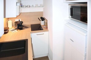 A compact kitchenette with a microwave, coffee maker, and a small sink.