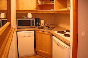 A compact kitchen with a microwave, coffee maker, sink, dishwasher, and stove.