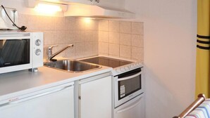 A compact kitchen with a built-in microwave, stainless steel sink, and oven. - 50m from resort center, 4th floor, balcony, 22m², Les Orres (Les Orres)