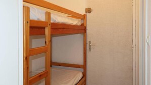 A bunk bed with a wooden frame and white bedding, a door with a metal handle, and a tiled floor. - 50m from resort center, 4th floor, balcony, 22m², Les Orres (Les Orres)
