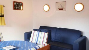 A room with a blue sofa, a round table with a blue tablecloth, and two wall-mounted lights. - 50m from resort center, 4th floor, balcony, 22m², Les Orres (Les Orres)