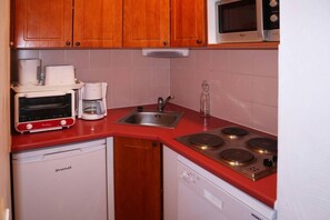 A compact kitchen with a red countertop, a toaster, a coffee maker, a microwave, and a dishwasher. - Ski-in/ski-out & foot of the slopes, 1st floor, swimming pool, sauna, balcony, tv, ski locker, 40m² (Les Orres)