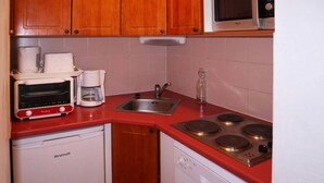 Una cocina compacta con armarios de madera, microondas, tostadora y cafetera.