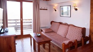 Una habitación acogedora con un sofá de madera, una mesita pequeña y un escritorio con teléfono.