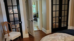 A bedroom with a bed, a chair, a rug, and a ceiling fan.