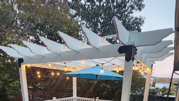 A covered deck with a fire pit, outdoor furniture, and string lights.