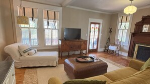 A living room with a sofa, ottoman, and a television on a wooden cabinet.