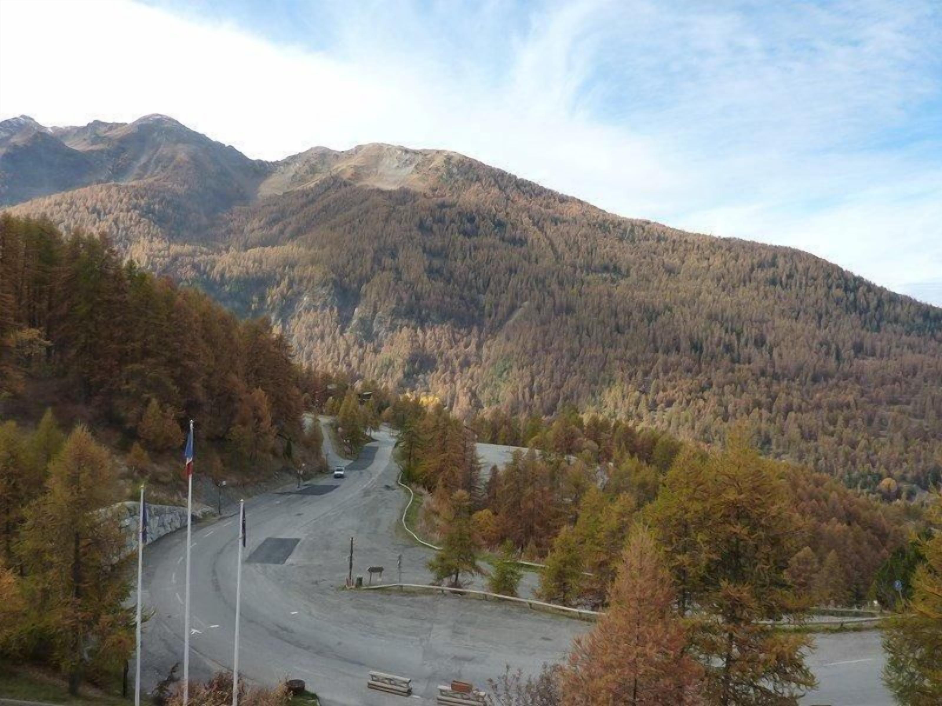 Eine gebirgige Landschaft, eine Straße schlängelt sich durch einen bewaldeten Bereich.