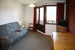 A room with a sofa, a table, a television, and a window with curtains. - Ski-in/ski-out & foot of the slopes, 7th floor, view valley, balcony, tv, 26m², Les Orres (Les Orres)