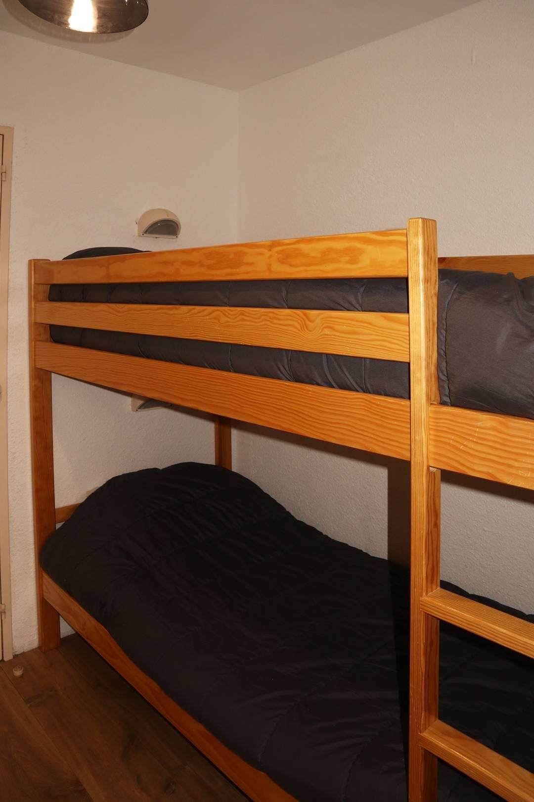 Een stapelbed met houten frame en zwarte beddengoed.