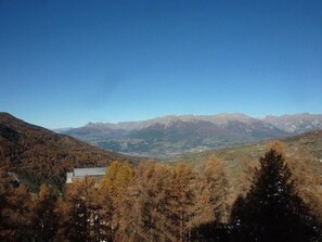 A mountainous landscape with a clear sky, a building with a metal roof, and dense forest in the foreground. - Ski-in/ski-out & foot of the slopes, 7th floor, view valley, balcony, 40m², Les Orres (Les Orres)