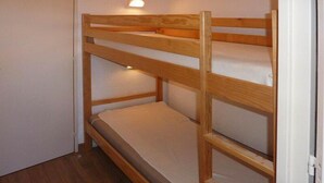 A bunk bed with a headboard and a wall-mounted light fixture.