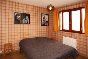 A bedroom with a bed, two framed pictures on the wall, a window with curtains, and a radiator. - Ski-in/ski-out & foot of the slopes, 7th floor, view valley, balcony, 40m², Les Orres (Les Orres)