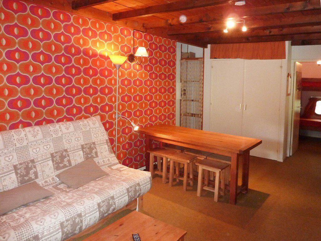 A cozy room with a patterned sofa, a wooden table, and a wall with a circular pattern.
