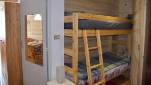A small, wooden cabin-style room with bunk beds, a desk, and a mirror. - 150m from resort center, 1st floor, balcony, parking, tv, ski locker, 26m², Montgenèvre (Montgenèvre)
