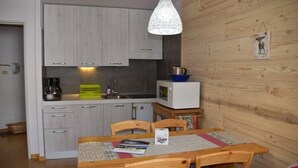 A compact kitchen with light wood cabinets, a microwave, and a hanging pendant light. - 150m from resort center, 1st floor, balcony, parking, tv, ski locker, 26m², Montgenèvre (Montgenèvre)