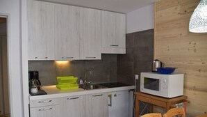 A compact kitchen with light wood cabinets, a built-in sink, a microwave, and a small refrigerator. - 150m from resort center, 1st floor, balcony, parking, tv, ski locker, 26m², Montgenèvre (Montgenèvre)