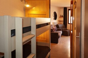 A room with bunk beds, a sofa, and a mirror.