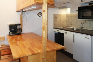 A compact kitchen with a wooden countertop, a coffee maker, a microwave, and a dishwasher.