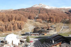 A mountainous landscape with a ski resort, including a restaurant, a large white dome structure, and a wooden building with a sloped roof.