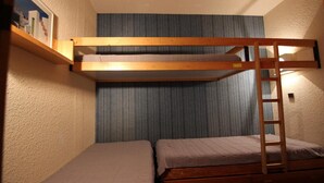Una cama litera con escalera, un escritorio pequeño y un cuadro en la pared.