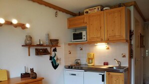 Eine kleine Küche mit Holzschränken, einer Mikrowelle, einer Kaffeemaschine und einem Geschirrspüler.