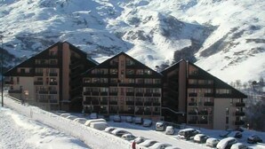 Ein Hotel mit mehreren Stockwerken, einem Parkplatz und einer Bergkulisse.