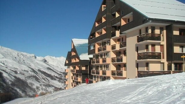 Ein mehrstöckiges Hotel mit modernem architektonischen Design, mit Balkonen und einer verschneiten Landschaft im Hintergrund.