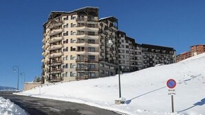 A multi-story building with balconies, a no parking sign, and a snow-covered slope. - 2nd floor, tv, ski locker, 24m², Les Menuires (Les Menuires)