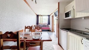 A compact kitchen with a dining area, wooden furniture, and a view to a living room. - 2nd floor, tv, ski locker, 24m², Les Menuires (Les Menuires)