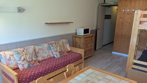 Ein kleiner Raum mit einer Holzsofa, einem kleinen Holzschrank und einem gefliesten Tisch.