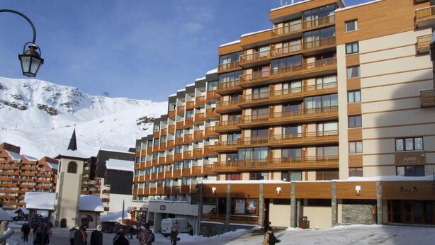 Ett hotell med flera våningar, balkonger, en central innergård och ett snötäckt berg i bakgrunden.