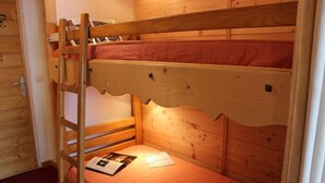 En våningssäng med en stege, träväggar och en röd madrass.