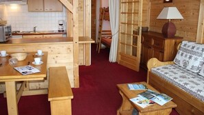 En mysig trästuga med ett litet kök, en matplats, en soffa och en säng.