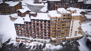 Ett hotell med flera våningar, balkonger, en parkeringsplats och en omgivning täckt av snö.