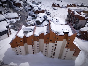 A multi-story hotel with a snow-covered roof, surrounded by a ski resort area. - 100m from resort center, 1st floor, balcony, ski locker, 24m², Val Thorens (Val Thorens)