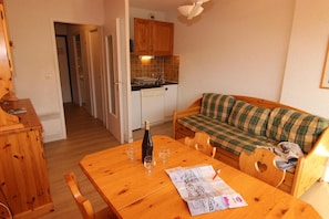 A cozy living area with a wooden table, a sofa, and a kitchen in the background.
